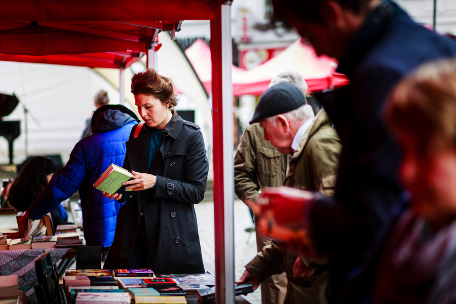 Een vrouw en enkele mensen bekijken boeken aan een kraampje. Een vrouw en enkele mensen bekijken boeken aan een kraampje.